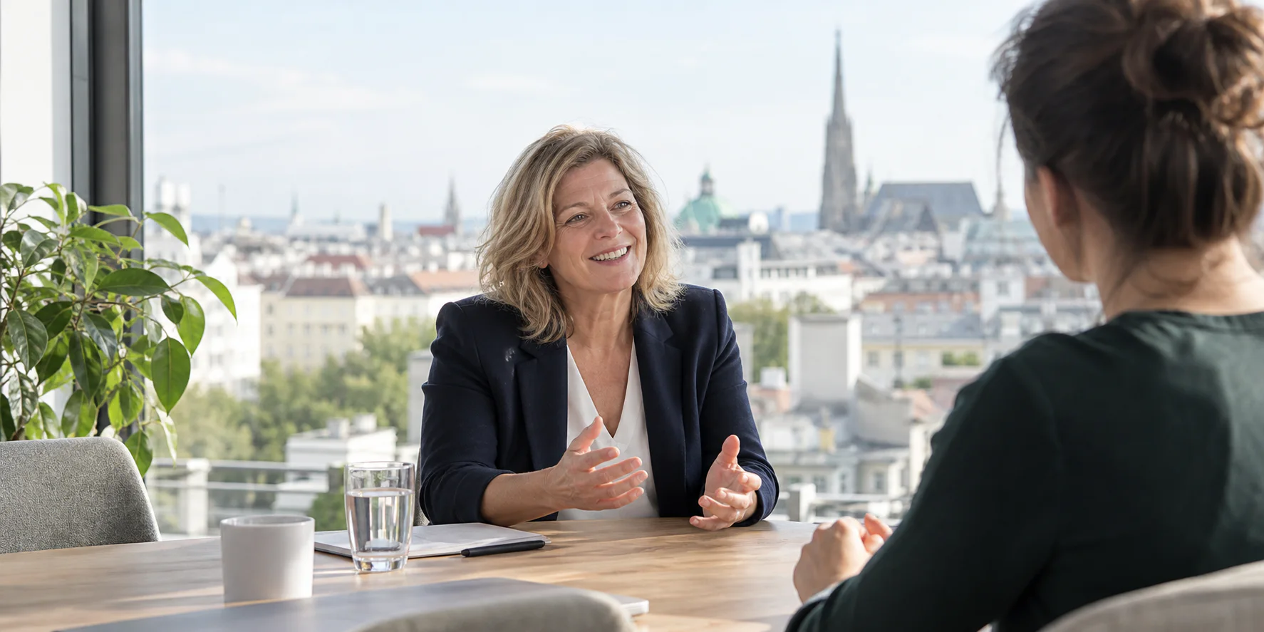 Berufserfahrene Frau im Bewerbungsgespräch mit Wiener Stadtblick